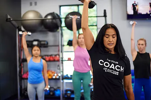 A coach in front of women exercising with dumbbells 
